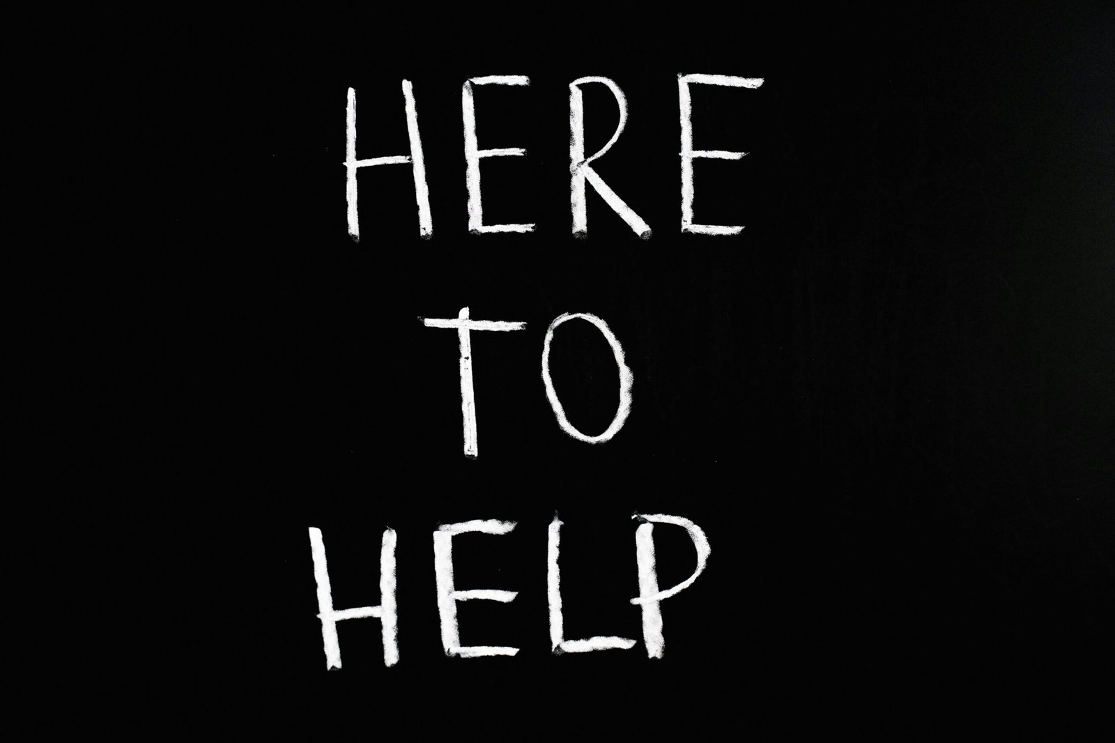 White text Here to Help on a minimalist black chalkboard background conveying encouragement and support
